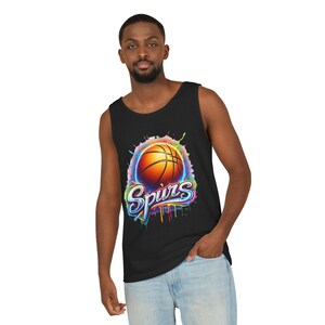May include: Black tank top featuring a vibrant basketball design with the word "Spurs" in colorful graffiti-style lettering. The basketball is orange with black lines, set against a splash of rainbow colors.