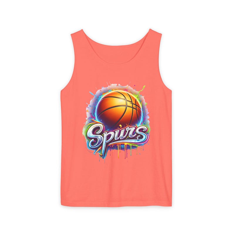 May include: Coral-colored tank top featuring a basketball graphic with the word "Spurs" in a stylized font. The basketball is orange with black lines, set against a colorful, splash-like background. A sporty apparel item.
