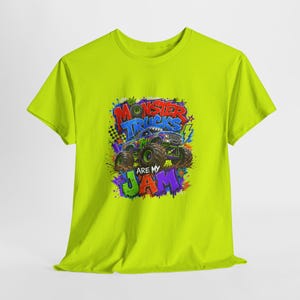 Może przedstawiać: Limonkowa koszulka z kolorową grafiką monster trucka i napisem "Monster Trucks Are My Jam". Projekt zawiera szachownicę, gwiazdy i plamy farby.
