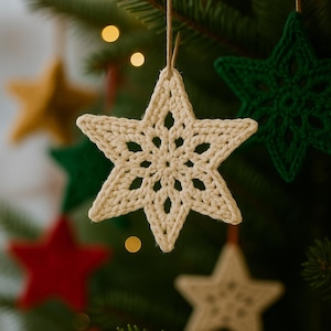 May include: Close-up of a cream-colored, crocheted star ornament hanging from a tree. The star has a detailed openwork design and is suspended by a natural twine. Other star ornaments in green, red, and gold are visible in the background.