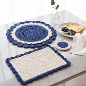 Peut inclure: Ensemble d'articles crochetés à la main, comprenant un dessous de plat rond, un dessous de plat rectangulaire et un dessous de verre. Les dessous de plat présentent un schéma de couleurs bleu et crème avec des bords festonnés. Le dessous de verre est bleu et crème.