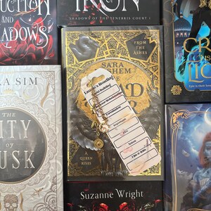 May include: A close-up of a book titled "A Kiss of Iron" with a bookmark that says "Laule's Reading" and has a list of topics including "World Building", "Character Relationships", "Foreshadow", "Important", "Plot", "Notes", "THG & ANG".
