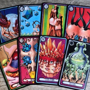 May include: A set of ten tarot cards with colorful illustrations. The cards feature a variety of imagery, including skulls, crystals, and a person with multiple faces. The cards are numbered from XII to XV. The text on the cards includes "Death", "Everything", and "Nothing".
