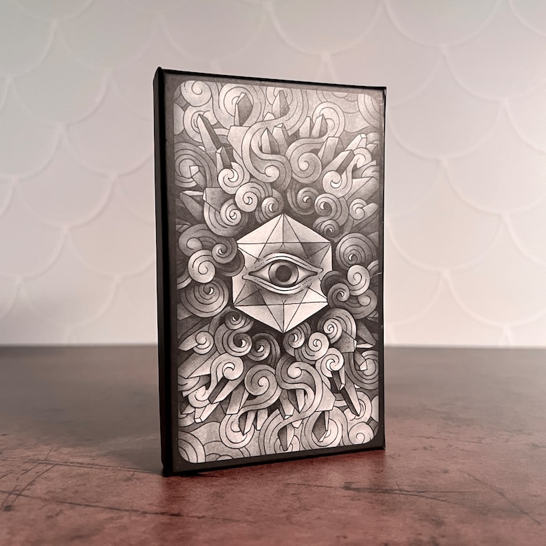 May include: Black and white illustration of a geometric eye with a swirling pattern around it. The eye is inside a black frame.