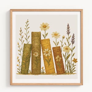 May include: A framed cross-stitch artwork depicting four stylized books in shades of green, yellow, and brown, with daisies and wildflowers growing from the tops. The artwork is in a light wooden frame.