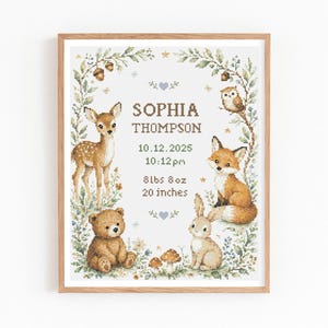 May include: A framed cross-stitch birth announcement featuring a deer, bear, fox, and rabbit surrounded by a floral wreath. Text includes SOPHIA THOMPSON, 10.12.2025, 10:12pm, 8lbs 8oz, and 20 inches, with small mushrooms and stars.