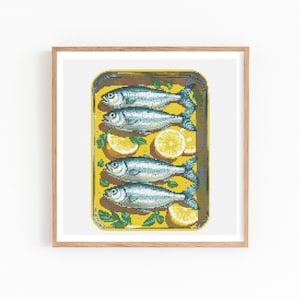 Può includere: Stampa incorniciata raffigurante una scatola gialla di sardine con fette di limone ed erbe. Le sardine sono argentate con pinne blu scuro. La stampa è in una cornice di legno.