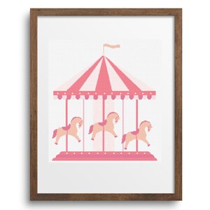 Puede incluir: Una impresión enmarcada con un diseño de carrusel rosa y blanco. El carrusel tiene un dosel a rayas y tres caballos en tonos de rosa y melocotón. La obra de arte está sobre un fondo blanco y enmarcada en un marco de madera marrón.