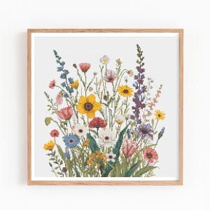 May include: A framed cross-stitch depicting a colourful wildflower bouquet. The artwork showcases various flowers, such as yellow sunflowers, red poppies, and blue cornflowers, against a white backdrop. The frame is made of light brown wood.