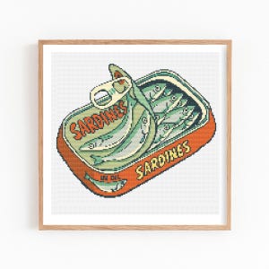 May include: A framed print of a pixelated illustration of a sardine can. The can is orange with the words "Sardines" in yellow. Inside the can are several green sardines. The can's lid is partially open.