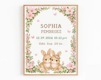May include: A framed cross-stitch birth announcement featuring the name "SOPHIA PEMBROKE", date, time, weight, and height. The design includes two bunnies, pink flowers, and butterflies. The frame is made of wood.