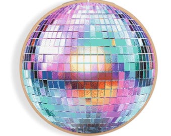 May include: A colorful disco ball with mirrored tiles in shades of pink, blue, and green. The ball is in a wooden embroidery hoop.