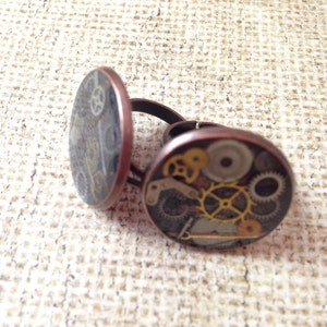 May include: Two copper rings with a steampunk design. The rings are decorated with a variety of gears and cogs.