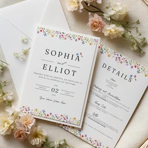 May include: Wedding invitation with a floral border. The invitation is white with black text and says "Sophia and Elliot" and "Friday, 02 June 2027". The details card is white with black text and says "Details" and "Parking and Accommodation".