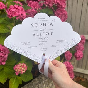 Może przedstawiać: Biały wachlarz ślubny z falistą krawędzią, z imionami "Sophia i Elliot" wydrukowanymi elegancką czcionką. Wachlarz zawiera szczegóły wesela, kwiatowe akcenty i białą wstążkę.