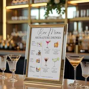May include: A framed bar menu with gold trim displays "Bar Menu Signature Drinks." The menu lists wine, spirits, beer, and non-alcoholic options with illustrations. Several martini glasses and other glassware are on the bar.