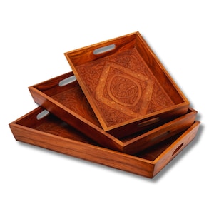 May include: A set of three rectangular wooden serving trays stacked on top of each other. Each tray features a rich brown finish and integrated handles on the sides. The top tray displays a central diamond-shaped carving with intricate floral patterns.