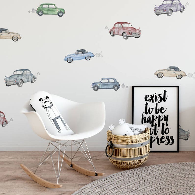 May include: A white rocking chair with a panda-themed pillow, a wicker basket with a toy inside, and a framed print with the text "exist to be happy, not to impress". The wall behind the chair is decorated with watercolor car stickers in various colors.