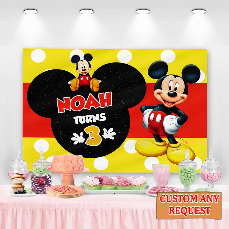 May include: A Mickey Mouse themed birthday party backdrop with the name "Noah" and the number "3". The backdrop is yellow with white polka dots, a red stripe, and a large Mickey Mouse head shape. Mickey Mouse is featured on the backdrop and the table is set with treats.