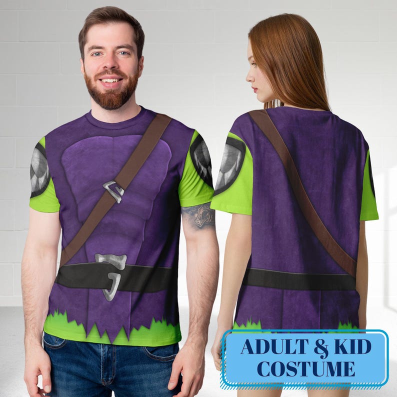 May include: Purple and green costume t-shirts with a brown strap and black belt design. The t-shirts have a jagged green hemline and a graphic on the sleeves. The text "ADULT & KID COSTUME" is displayed on a blue rectangle.