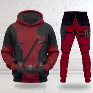 May include: A matching set consisting of a long-sleeve hooded sweatshirt and trousers featuring a red and black colour scheme. The hoodie includes a printed utility belt and shoulder strap design. The trousers feature printed holsters and pouches.