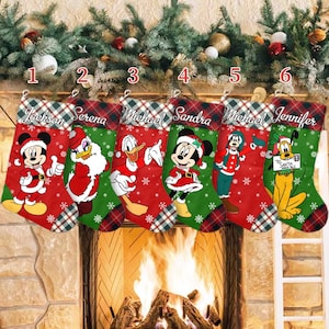 May include: Six Christmas stockings with cartoon characters, including Mickey Mouse, Donald Duck, and Minnie Mouse. Each stocking has a name embroidered at the top and a red and green plaid cuff. The stockings are red and green with snowflake designs.