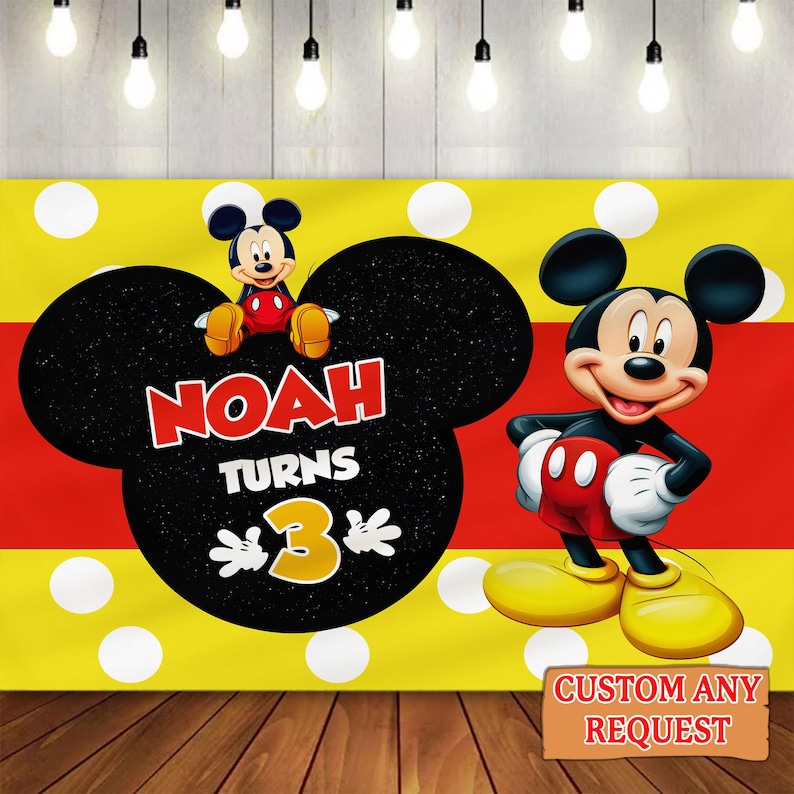 May include: A yellow and red backdrop with white polka dots and a large black Mickey Mouse head shape. The text "NOAH TURNS 3" is displayed. A cartoon Mickey Mouse character is on the right. The words "CUSTOM ANY REQUEST" are on a brown sign.