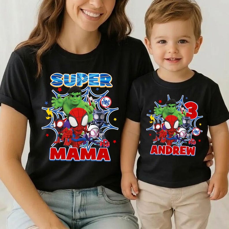 May include: Black t-shirts with superhero graphics. One shirt says "SUPER MAMA" and features Hulk, Spider-Man, and other characters. The other shirt says "ANDREW" with the number "3" and similar superhero graphics.