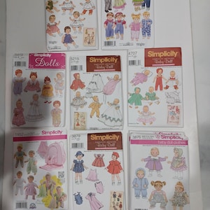 May include: A collection of Simplicity sewing pattern envelopes for baby dolls and doll clothes. The envelopes feature illustrations of dolls in various outfits, with text including "Baby Doll" and pattern numbers.