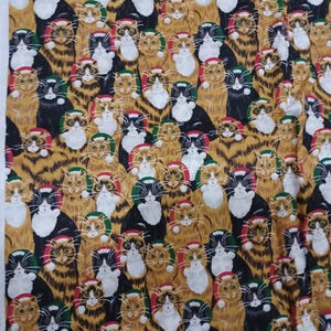 May include: Fabric with a repeating pattern of cats wearing Santa hats. The cats are in various colors, including black, orange, and white, with red, green, and white hats. The background is a mustard yellow.