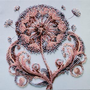May include: A beaded artwork depicting a dandelion. The seed head is in shades of pink, brown, and grey, with fine stems and leaves. The artwork is set against a pale blue background. The piece is likely a decorative item.