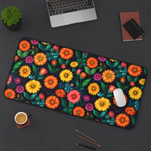 Op de afbeelding: Een rechthoekige bureaumat met een levendig bloemenpatroon. Het ontwerp toont een donkere achtergrond versierd met kleurrijke bloemen in tinten geel, oranje, roze en paars, samen met groene bladeren. Een witte computermuis ligt op de mat.
