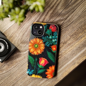 Op de afbeelding: Een zwarte smartphonehoes met een levendig bloemenontwerp met oranje zonnebloemen, rode en oranje rozen en groene bladeren. De hoes heeft een glanzende afwerking.