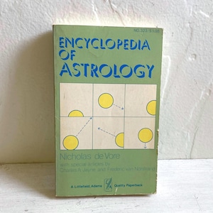 May include: A vintage paperback book titled "Encyclopedia of Astrology" with a green cover and blue lettering. The cover features a grid design with yellow circles and lines. The author's name, Nicholas de Vore, is also visible.