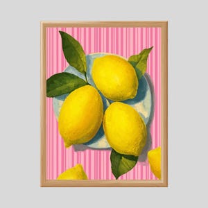 Può includere: Una stampa artistica incorniciata con una natura morta di limoni. Tre limoni giallo brillante poggiano su un piatto azzurro, circondati da foglie verdi. Lo sfondo è un motivo a righe rosa e bianche.