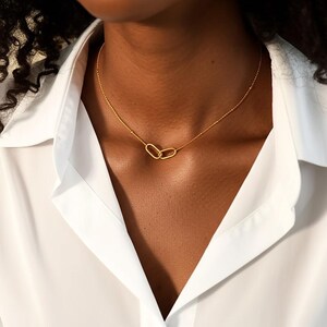 Puede incluir: Un collar de cadena de oro con dos colgantes ovalados unidos.