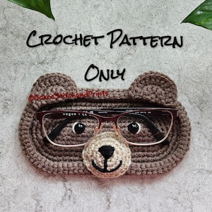 Könnte beinhalten: Gehäkelter brauner Brillenhalter in Bärenform mit einer Brille darauf. Der Text "CROCHET PATTERN ONLY" steht über dem Bären.