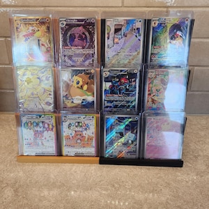 May include: A collection of 12 Pokemon trading cards displayed in a clear plastic card holder. The cards feature various Pokemon characters, including Pikachu, Charizard, and others. The cards are in excellent condition and are perfect for collectors.