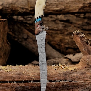 May include: A handcrafted knife with a curved, patterned blade. The handle features a bone grip, turquoise accents, and a wooden base with a decorative emblem. The knife is displayed against a backdrop of weathered wood.