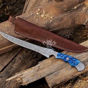 May include: A Damascus steel knife with a long, curved blade and a blue and white handle. The knife rests on a wooden surface next to a brown leather sheath. The handle has a red accent.