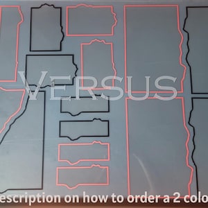 May include: A grey surface featuring shapes outlined in black and red. The word "VERSUS" is displayed in white. Text at the bottom reads "See Description on how to order a 2 colour set!"