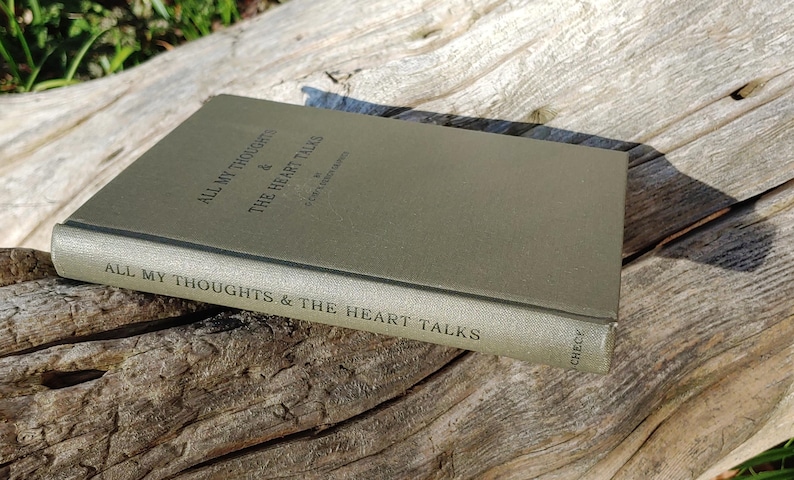 Puede incluir: Un libro de tapa dura verde apagado titulado "ALL MY THOUGHTS & THE HEART TALKS" sobre una superficie de madera envejecida. El t&iacute;tulo est&aacute; impreso en un color m&aacute;s oscuro. El lomo del libro tambi&eacute;n muestra el t&iacute;tulo.