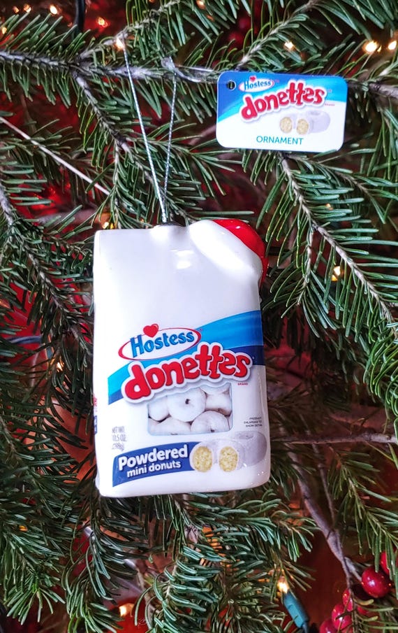 A glass Christmas ornament shaped like a Hostess Donettes snack pack — hyper-specific junk food nostalgia immortalized as holiday decor is peak white elephant energy.