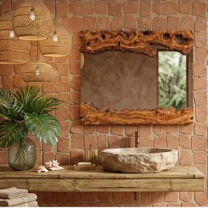 May include: A rustic bathroom scene featuring a large, rectangular mirror with a unique, natural wood frame. The mirror hangs above a stone sink on a wooden vanity. Woven pendant lights and a brick wall complete the natural aesthetic.
