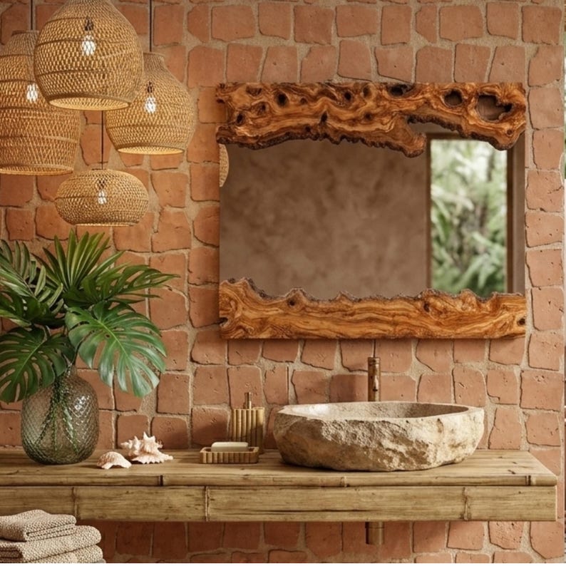 May include: A rustic bathroom scene featuring a large, rectangular mirror with a unique, natural wood frame. The mirror hangs above a stone sink on a wooden vanity. Woven pendant lights and a brick wall complete the natural aesthetic.