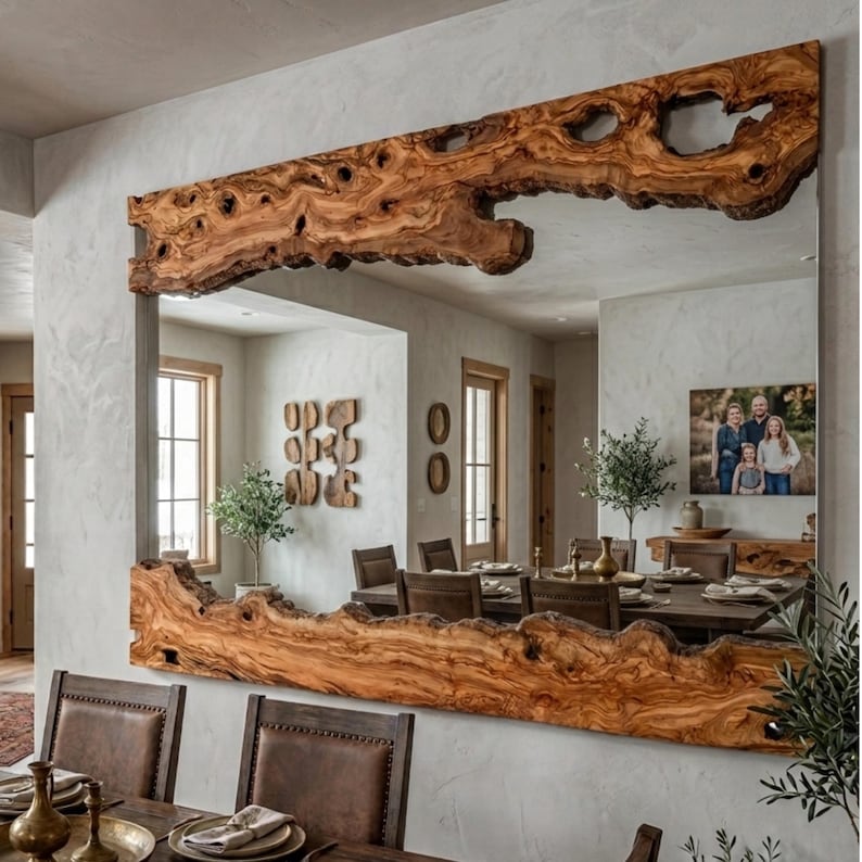 May include: Large rectangular mirror with a natural wood frame. The frame is made from a single piece of light brown wood with a live edge, featuring knots and organic shapes. The mirror reflects a dining room.