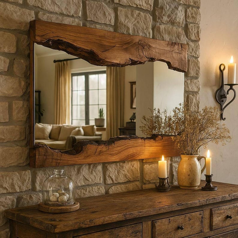 May include: A rectangular mirror with a natural wood frame, mounted on a stone wall. The frame has a live edge design. A wooden dresser with drawers is below the mirror. Lit candles and a vase with dried flowers are on the dresser.