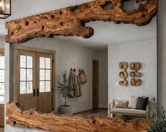 May include: A large rectangular mirror with a natural wood frame. The frame is made from a single piece of raw-edge wood, showcasing the wood's grain and knots. The mirror is mounted on a light-colored wall, reflecting the room's interior.