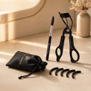 May include: A black eyelash curler, a spoolie brush with a black handle, five curved black silicone replacement pads, and a black drawstring pouch. The pouch and brush handle feature the gold text Beauty Power with a logo.