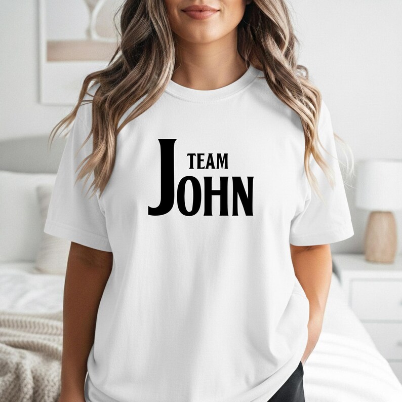 A person wearing a white t-shirt with the words Team John printed in large black text on the chest.